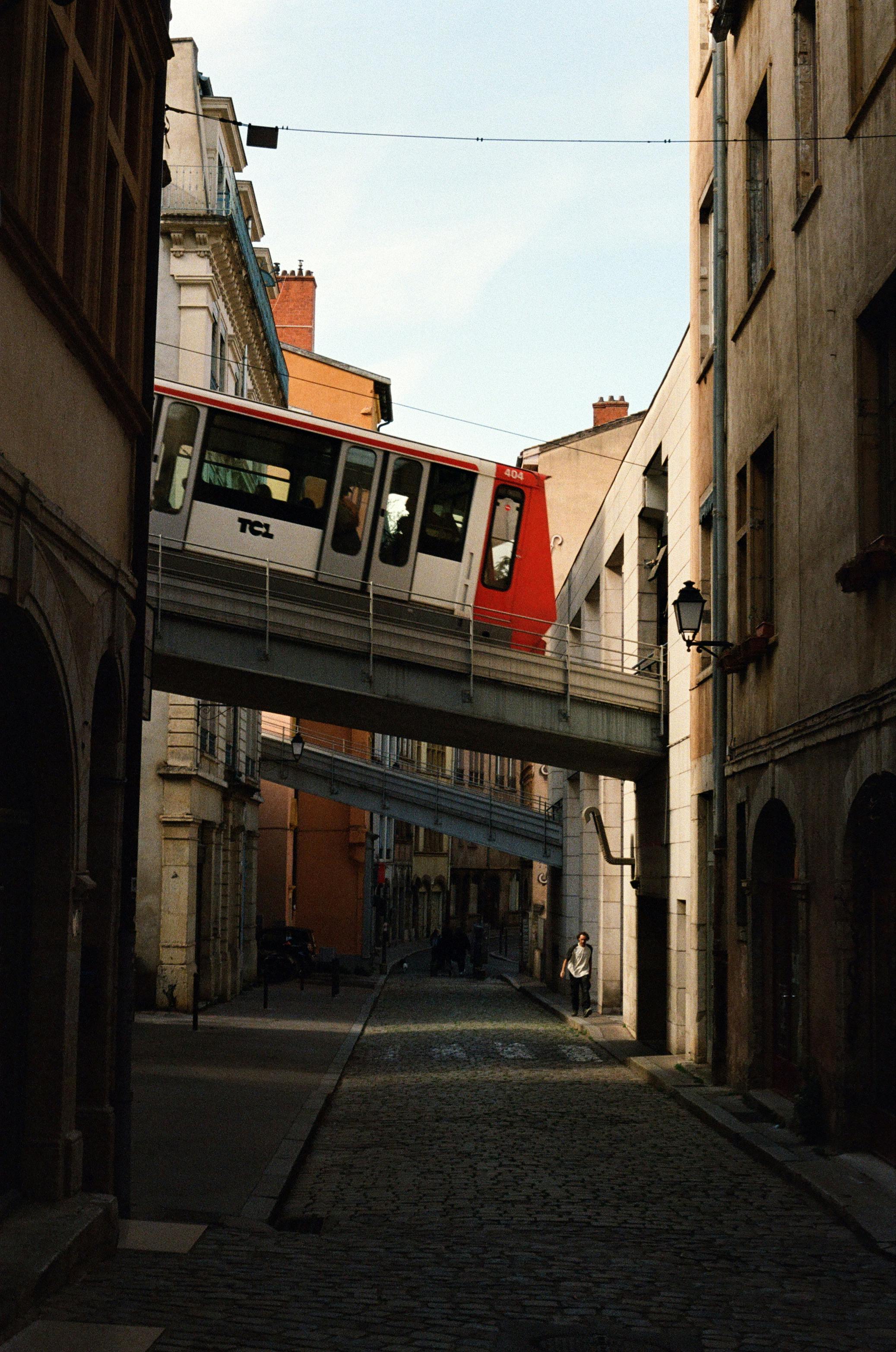 A scenic view of a historical funicular passing above a cobblestone street in Old Town Lyon, France.