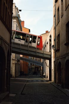 A scenic view of a historical funicular passing above a cobblestone street in Old Town Lyon, France.