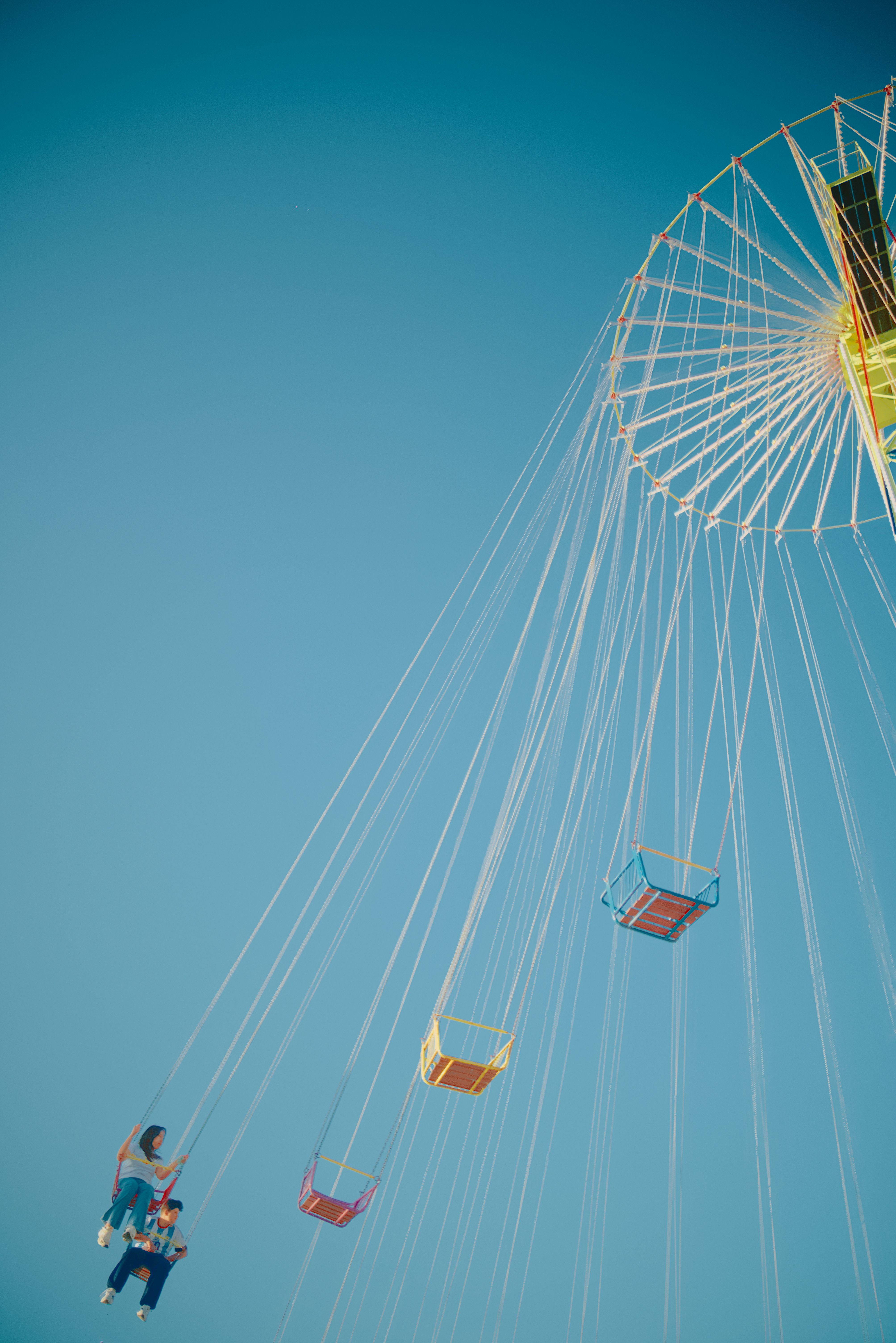 A vibrant swing carousel ride set against a clear blue sky, capturing summer fun.