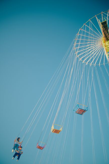 A vibrant swing carousel ride set against a clear blue sky, capturing summer fun.