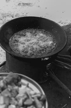 Monochrome image of a frying pan cooking outdoors, capturing rustic cooking vibes.