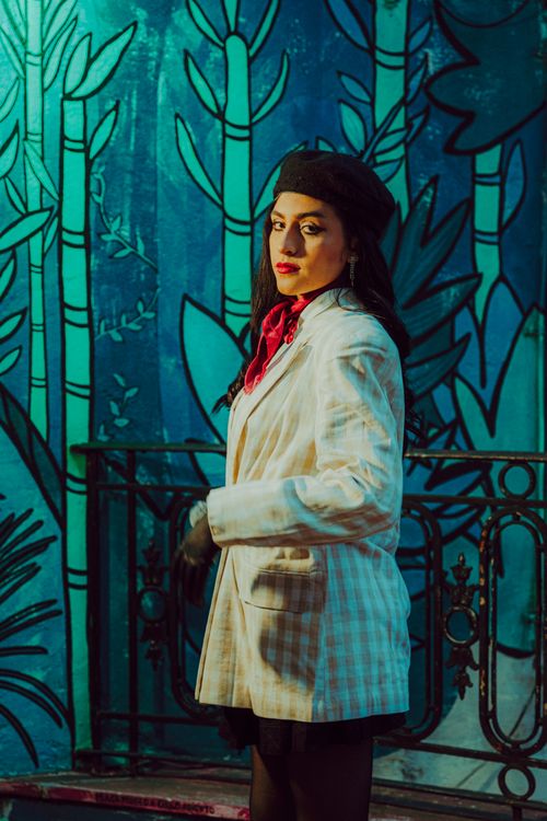Free Stylish woman posing by a vibrant wall mural with bold colors. Stock Photo