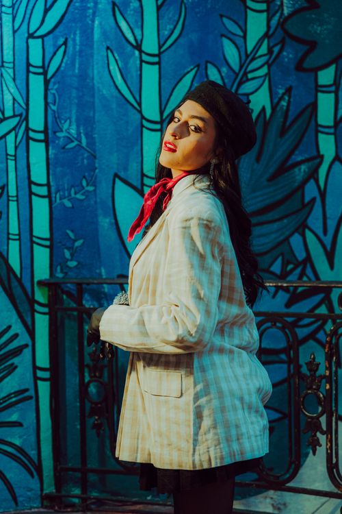 Free Stylish woman in plaid jacket and beret posing by a colorful mural. Chic and artistic. Stock Photo