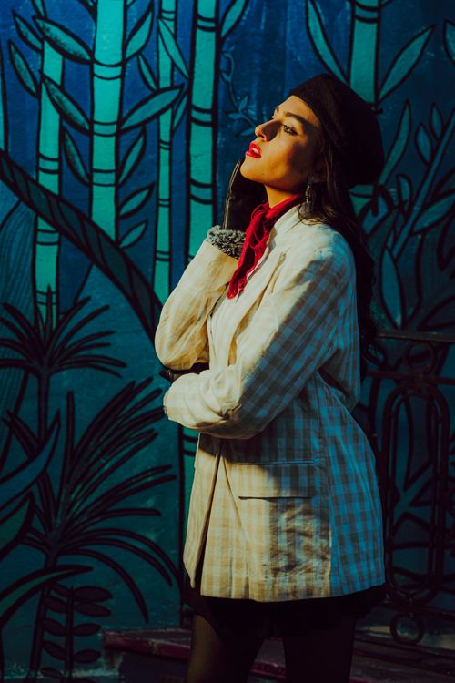 Free Fashionable woman poses in vintage attire with a vibrant artistic background. Stock Photo