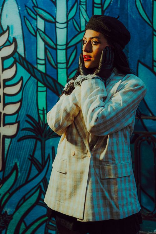 Free Fashionable woman in a hat posing against colorful graffiti wall during the day. Stock Photo