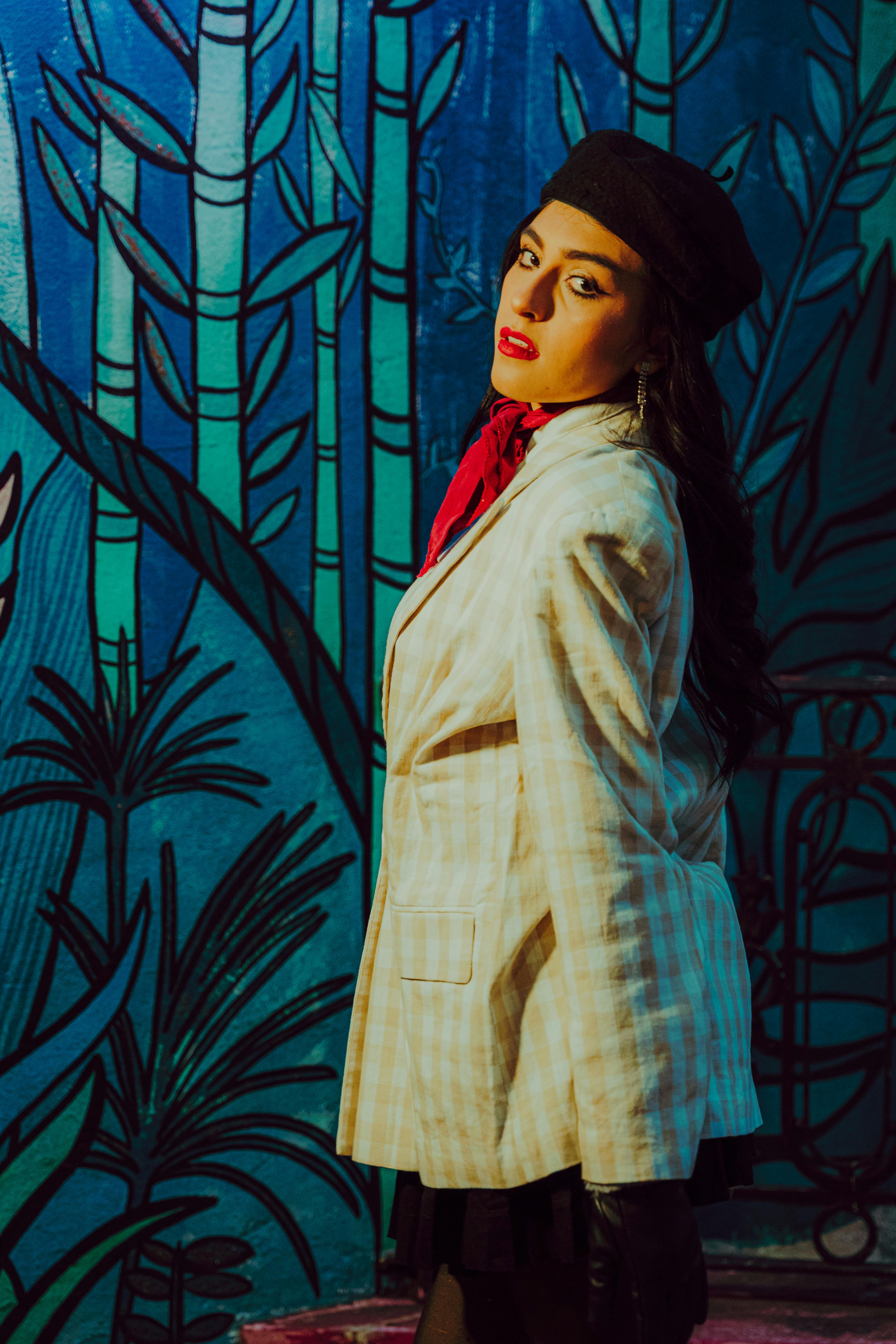 Free Stylish woman in a beret and blazer posing against a vibrant street mural. Stock Photo