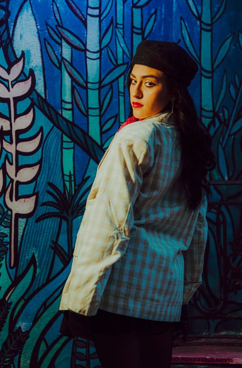 Free Artistic portrait of a woman in stylish attire against a colorful urban mural background. Stock Photo