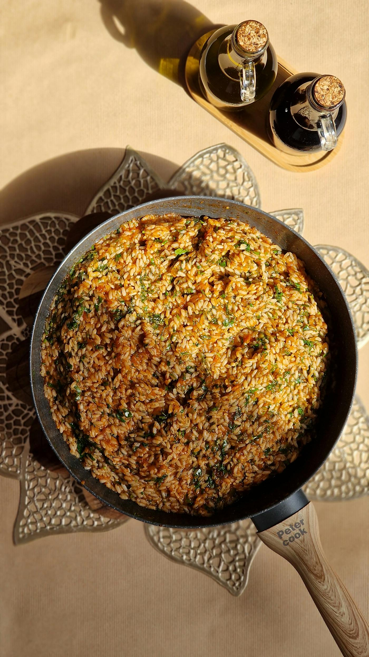 Padella vista dall'alto con risotto cremoso e erbe vicino all'olio