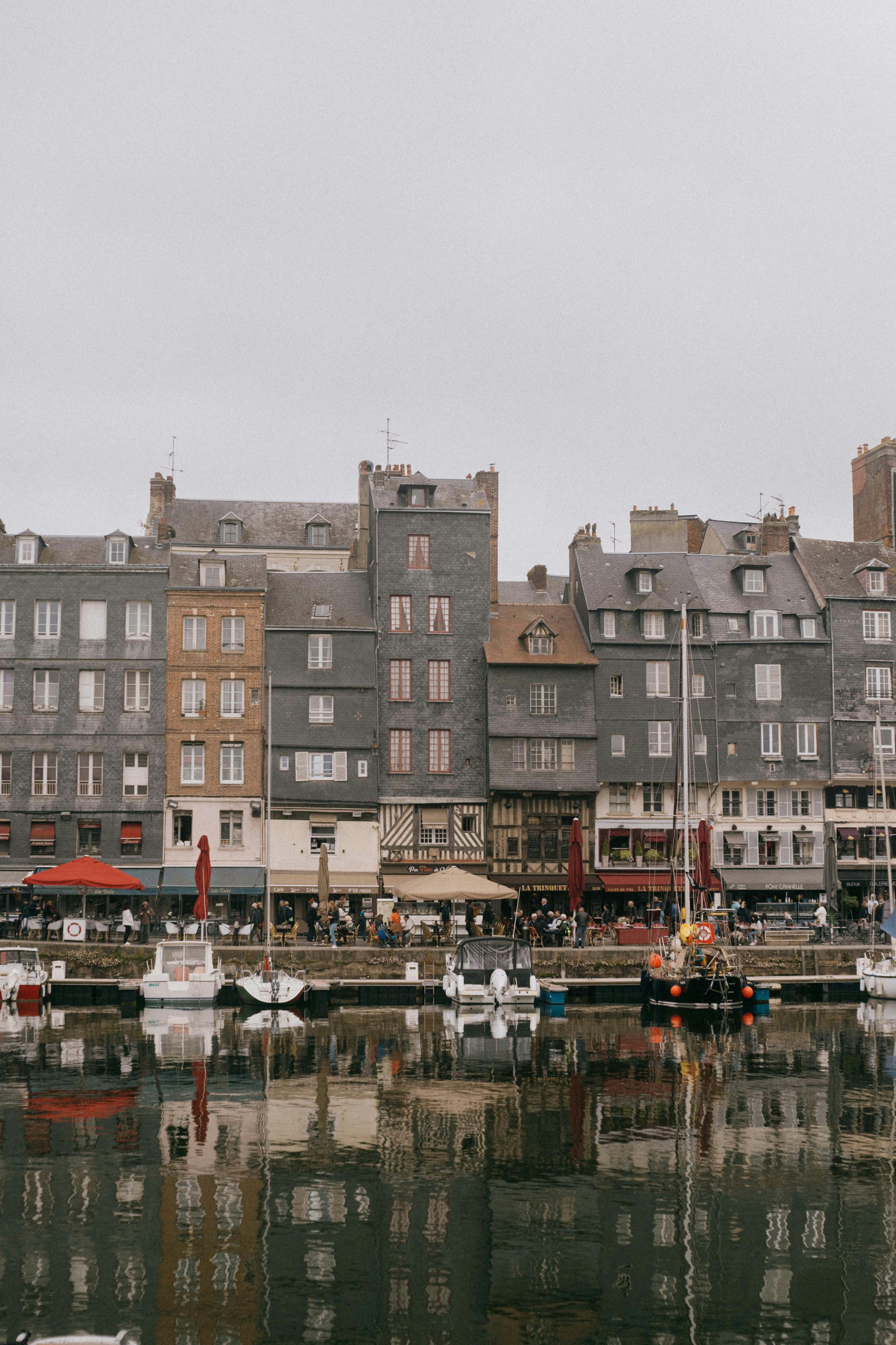 Charming old buildings reflect in the water at Honfleur's scenic port.