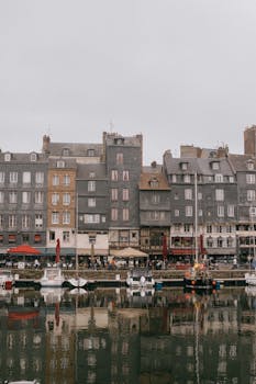 Charming old buildings reflect in the water at Honfleur's scenic port.