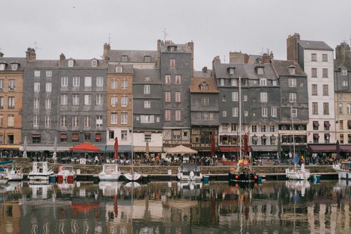 Free Charming historic buildings lining the old harbor in Honfleur, France, reflected in the water. Stock Photo