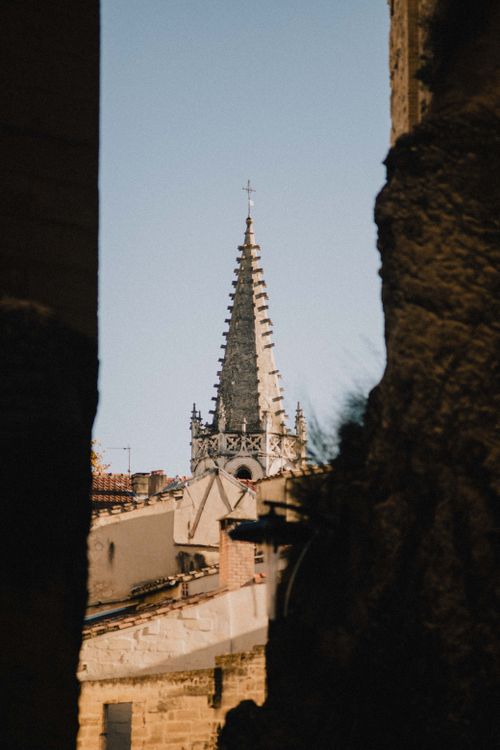 Free A captivating view of a Gothic church spire framed by ancient stone walls in Avignon, France. Stock Photo