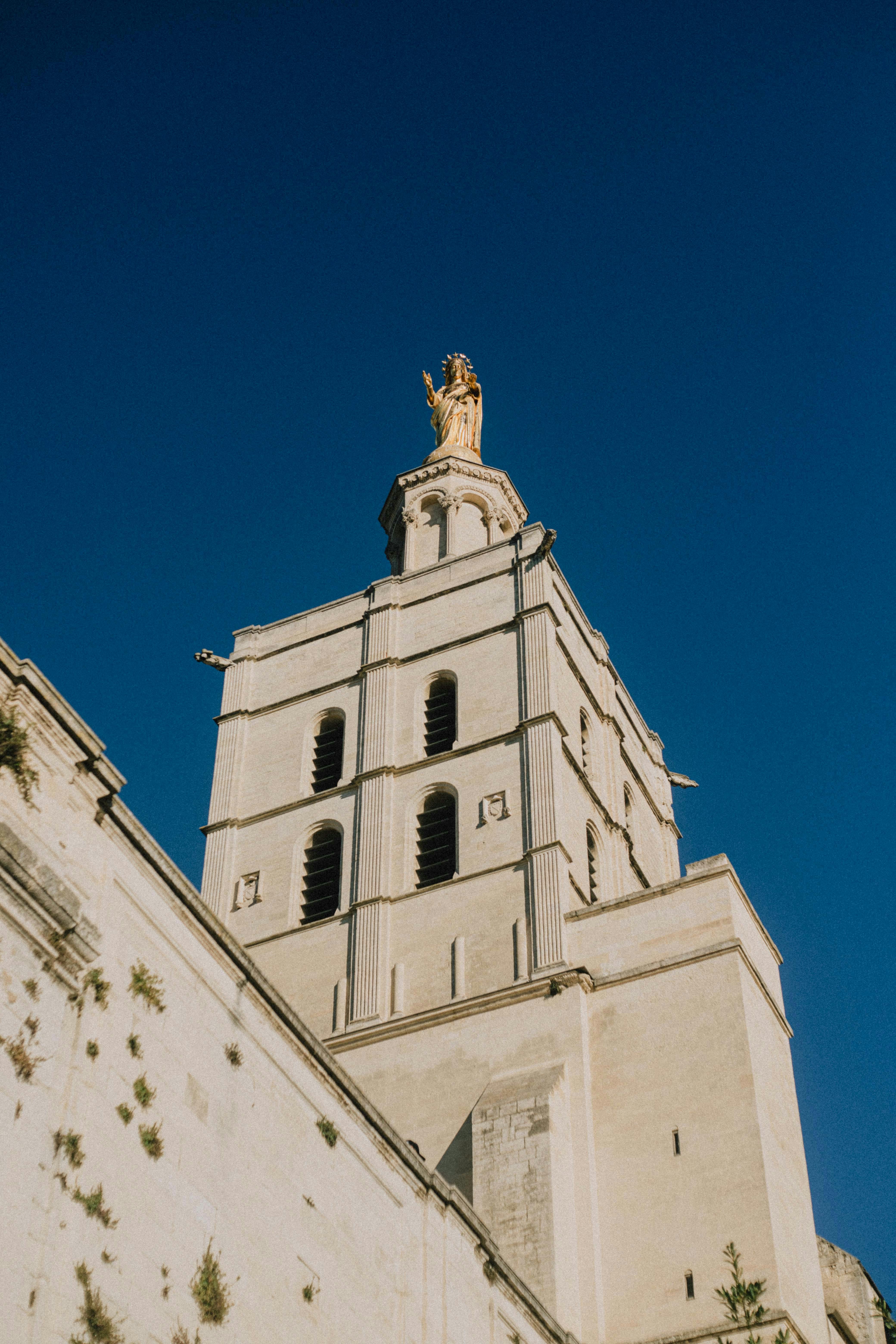 View of Avignon Cathedral's bell tower with a blue sky backdrop in Provence, France.