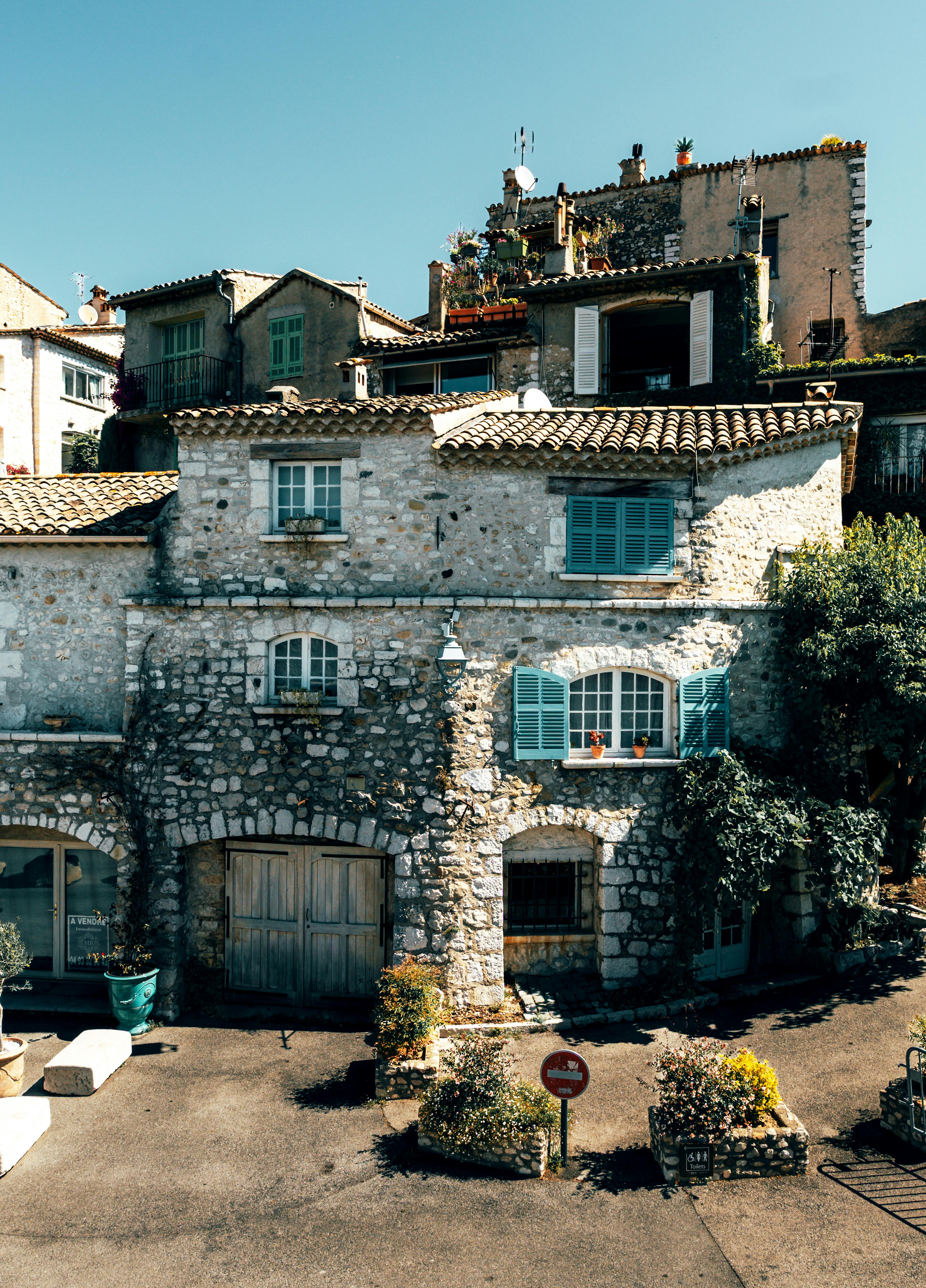 Old stone house with blue shutters in sunny Provence, France, showcasing rustic architecture.