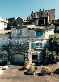 Old stone house with blue shutters in sunny Provence, France, showcasing rustic architecture.
