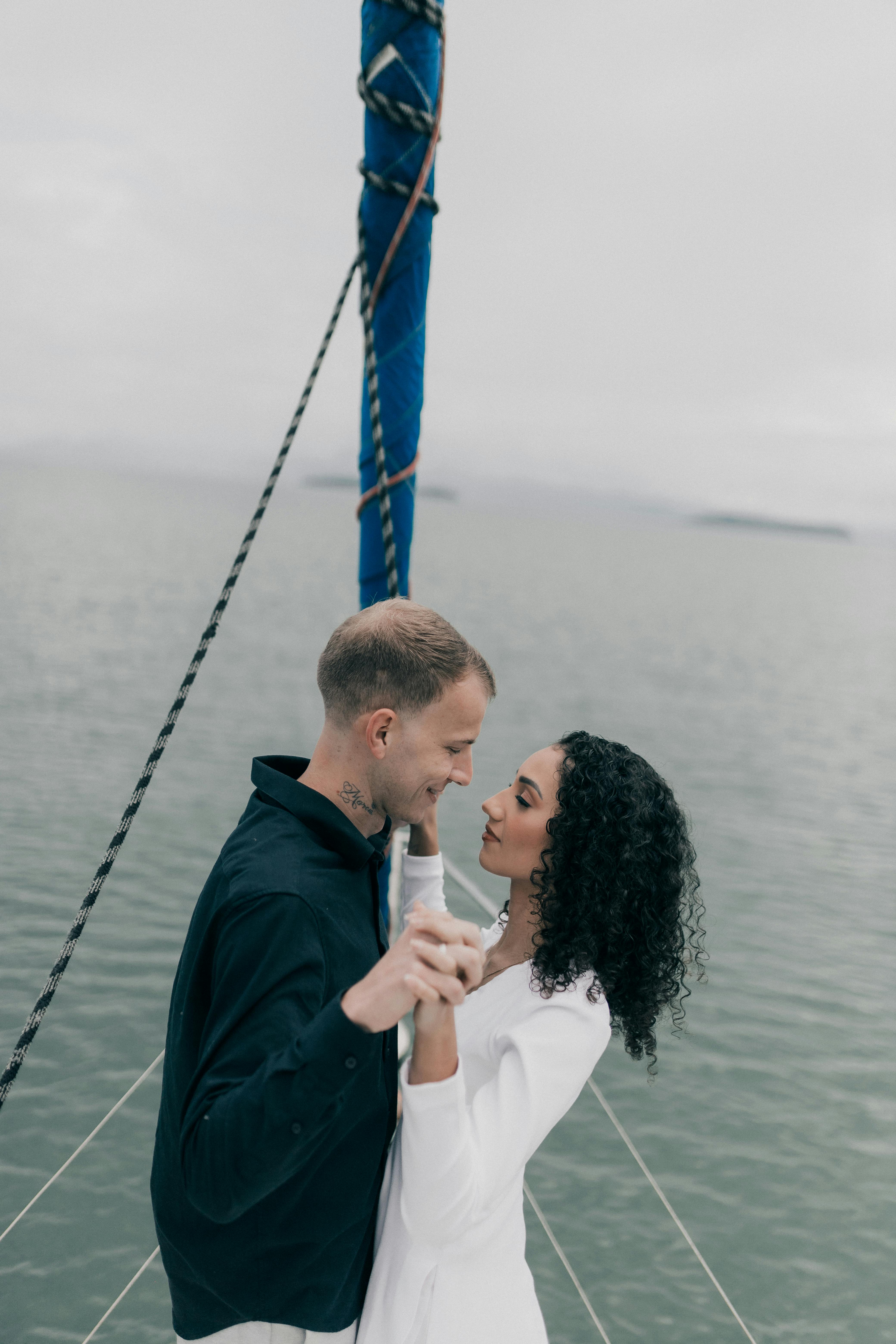 A loving couple embraces on a boat with a serene sea backdrop, showcasing romance and adventure.