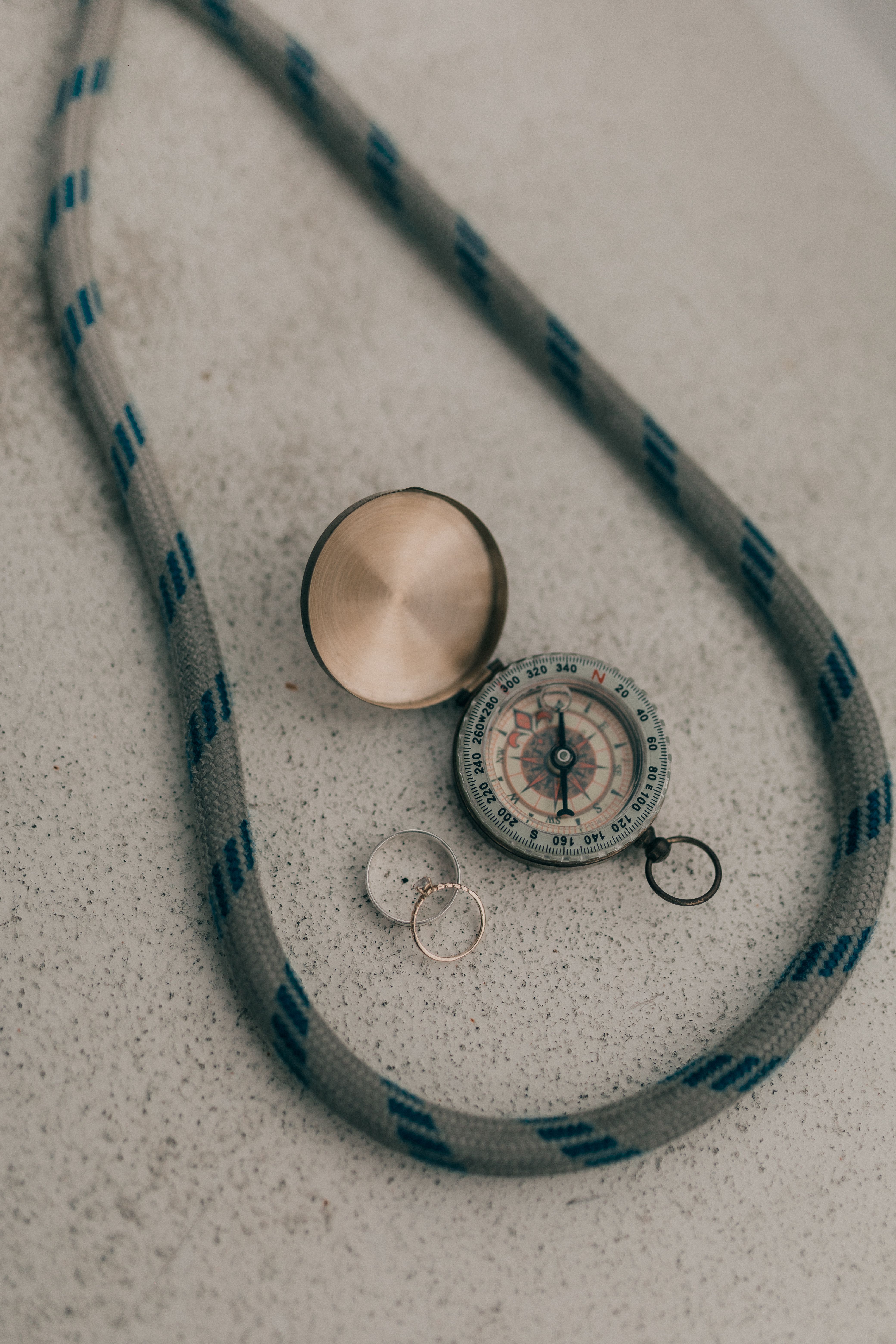 A vintage compass placed inside a rope circle on a textured concrete surface.