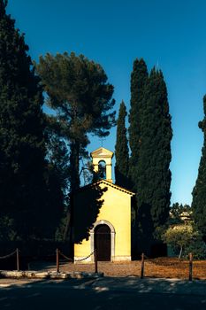 Serene yellow chapel amidst tall cypress trees in Vence, Provence-Alpes-Côte d'Azur, France.