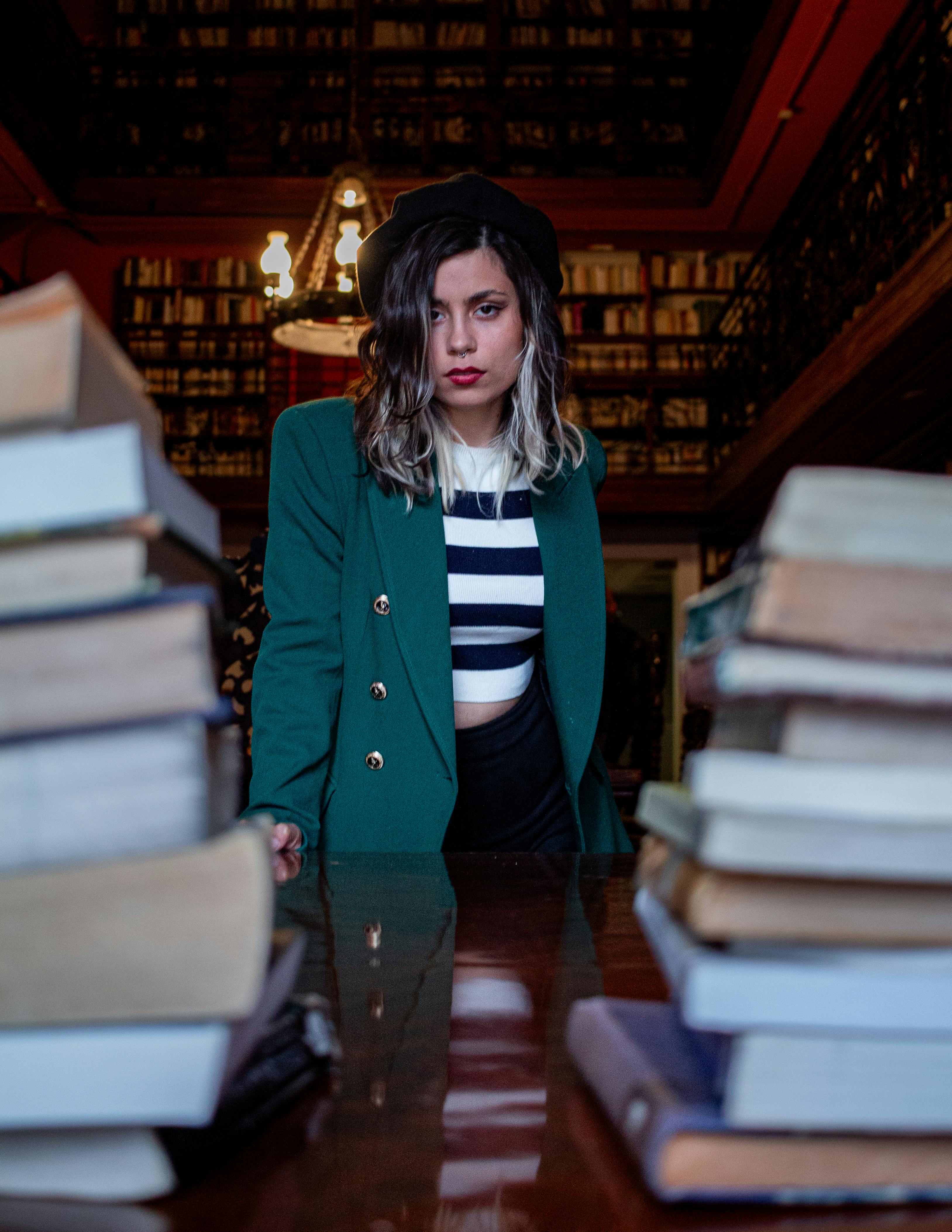 Gratis En moderigtig kvinde står i et klassisk bibliotek med bøger i Buenos Aires, Argentina. Lagerfoto