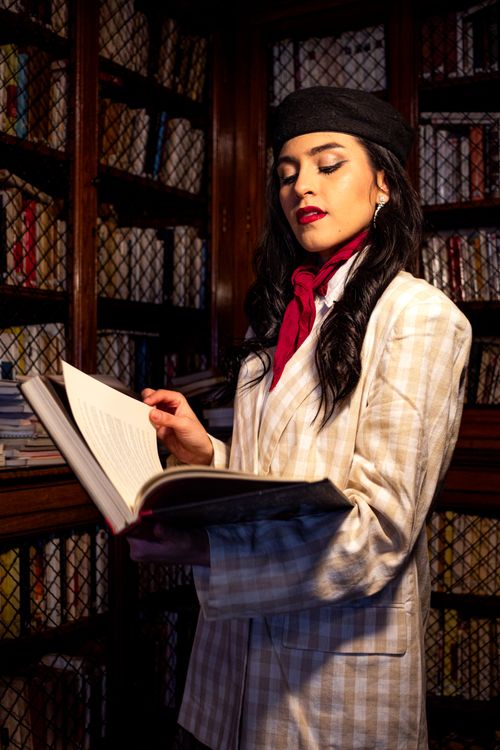 Free A fashionable woman reads in a classic Buenos Aires library, wearing a beret and scarf. Stock Photo