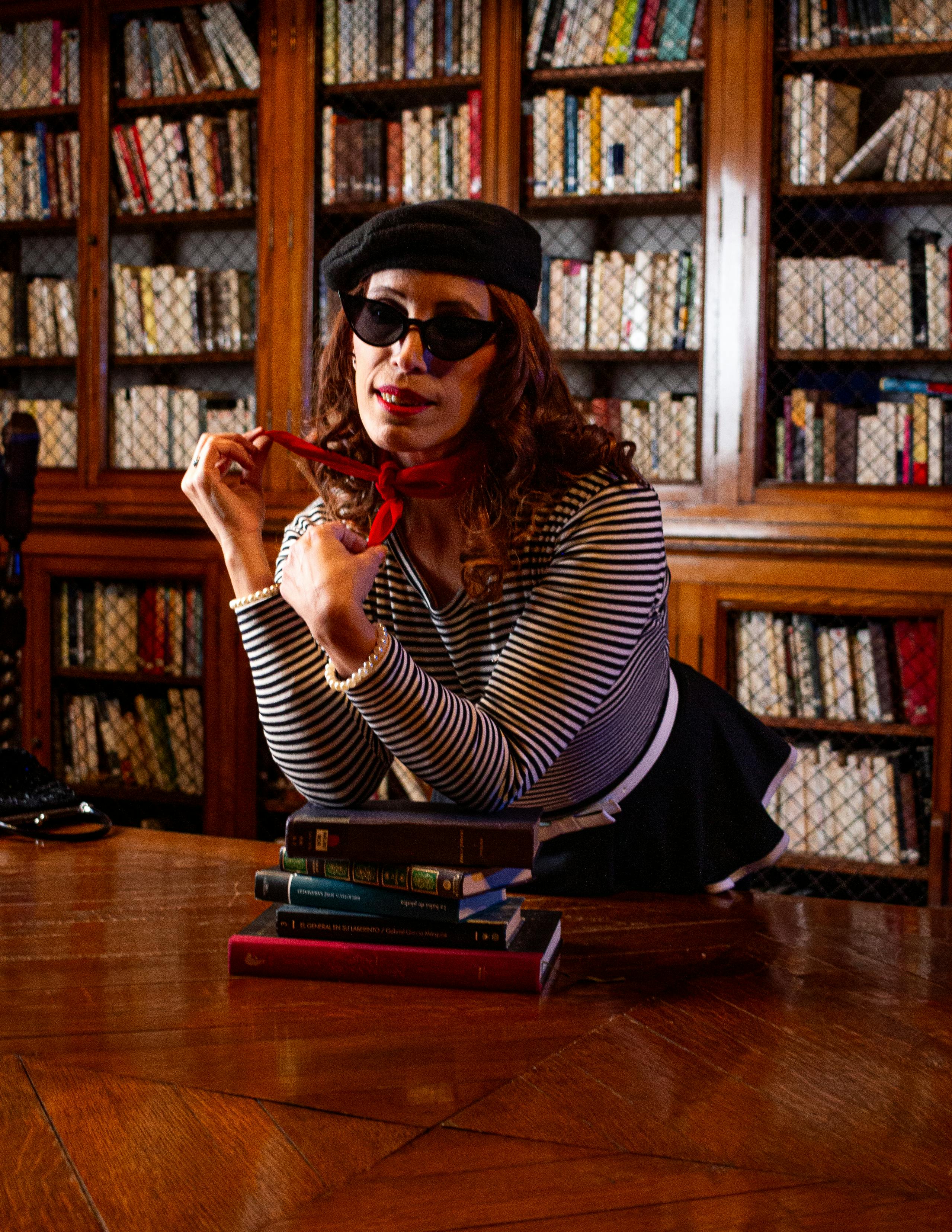 Gratis Mujer elegante en un entorno de biblioteca vintage, con gafas de sol y una boina. Foto de stock