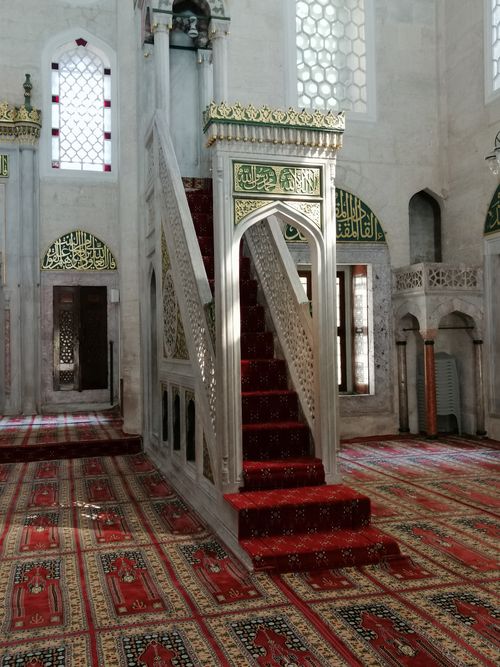 Free Sunlit Ottoman mosque interior featuring a traditional pulpit with colorful carpet. Stock Photo
