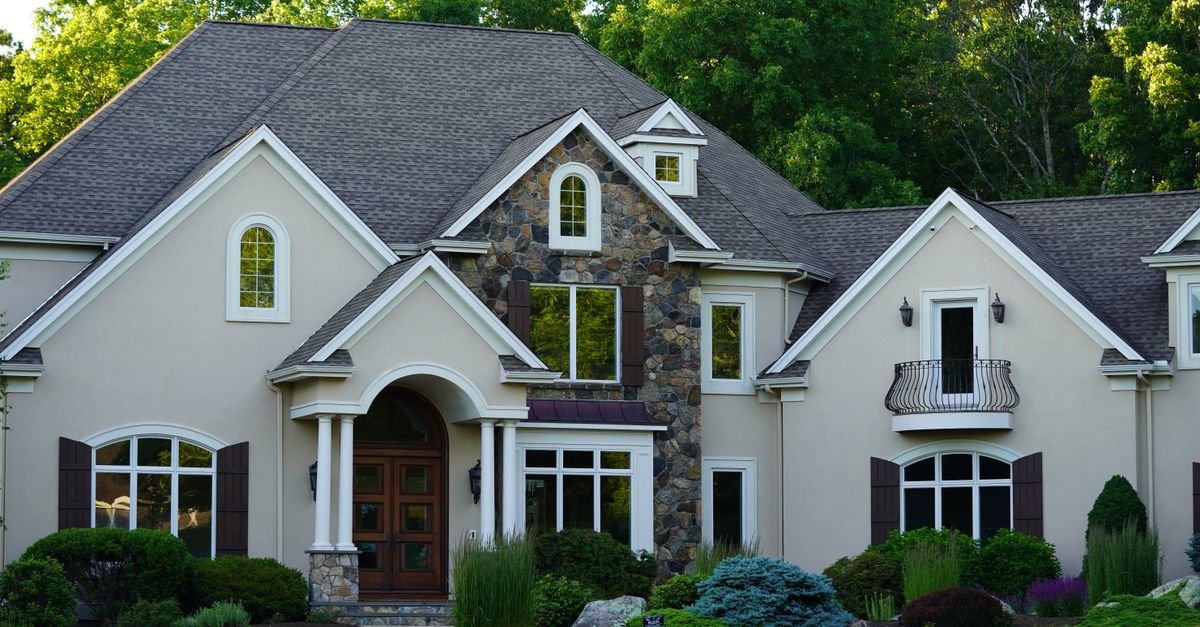 A picturesque view of a large suburban house surrounded by lush greenery.