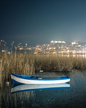 Serene nightscape of Ohrid, North Macedonia, featuring a calm lake with boat reflection.