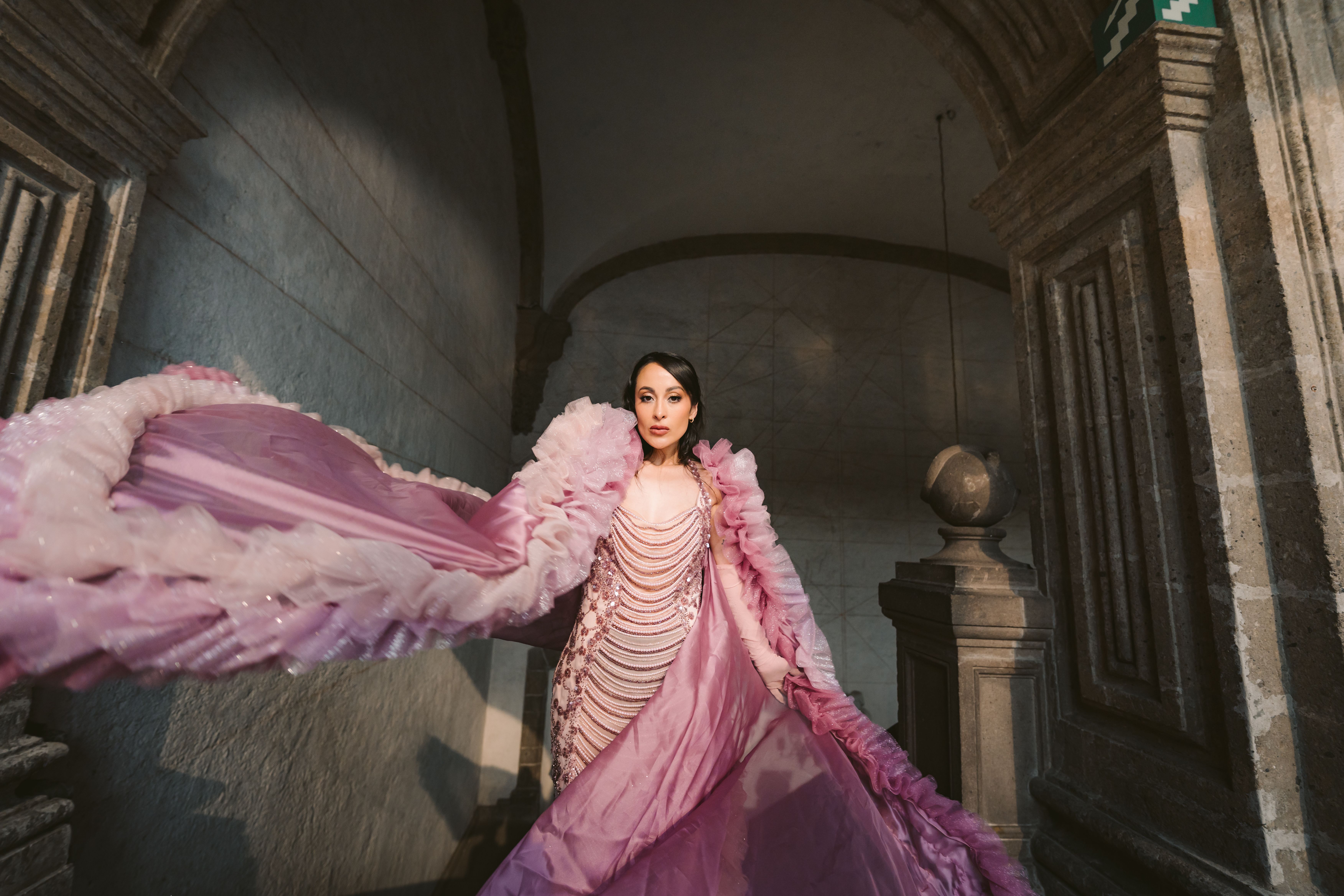 Woman in a flowing pink gown in a historic building, capturing elegance and drama.