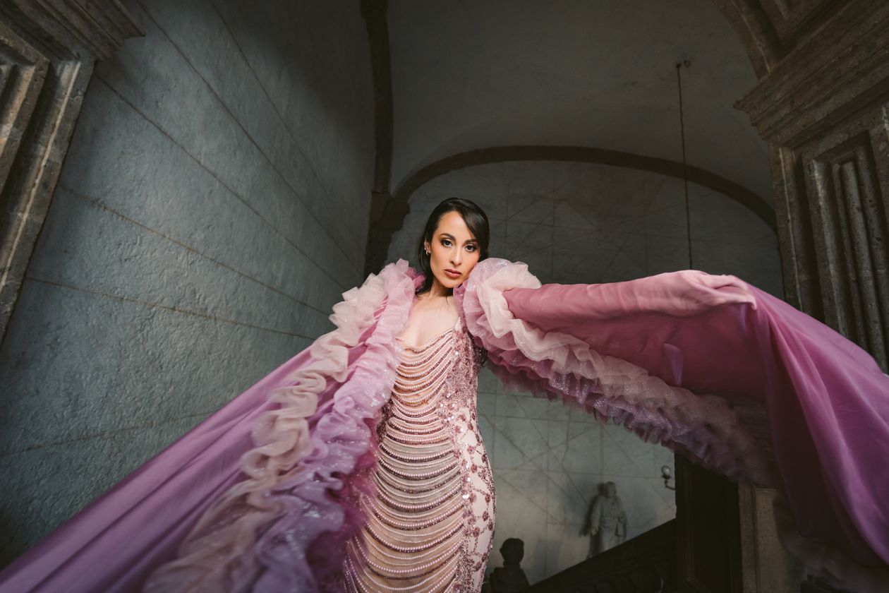 Woman in a mauve beaded gown with a ruffled shawl in a classical stone interior