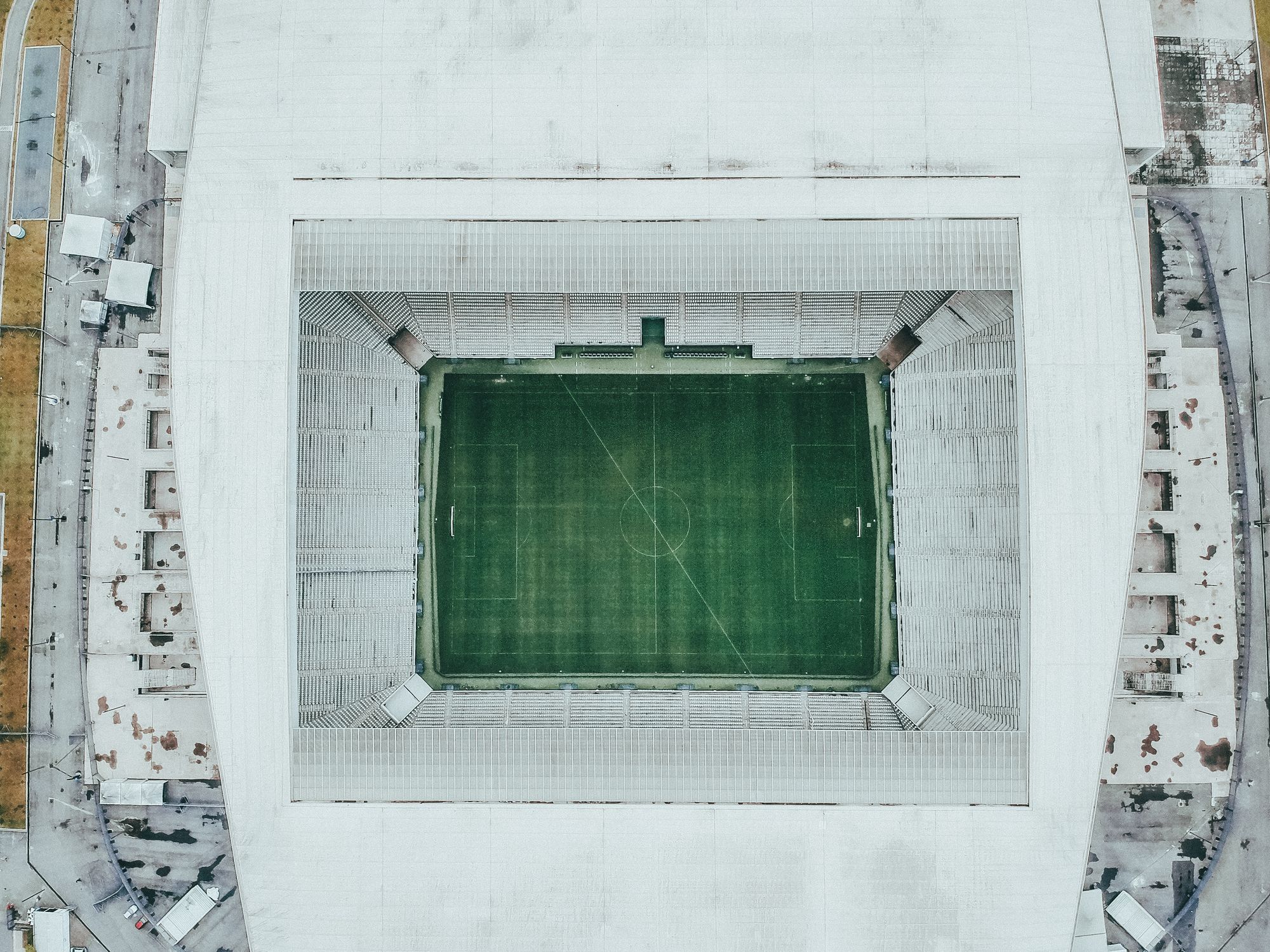 Top-down shot of an empty soccer stadium with green field and white stands.