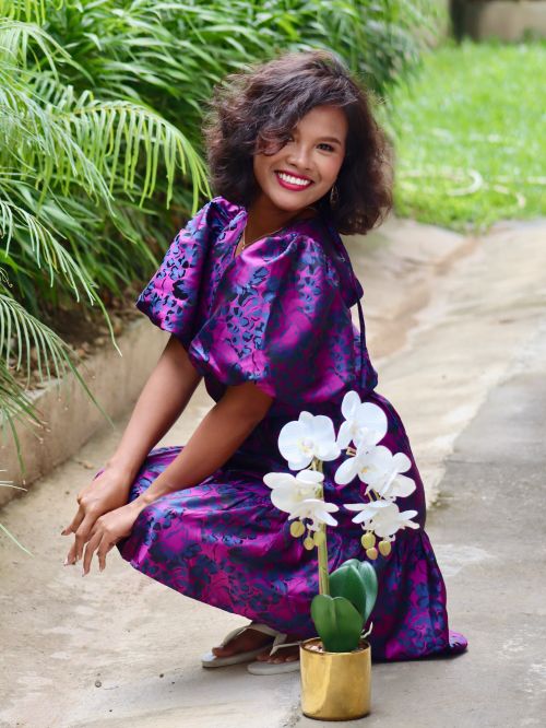 Free An Asian woman with a beautiful smile kneeling beside white orchids, outdoors in Talisay. Stock Photo