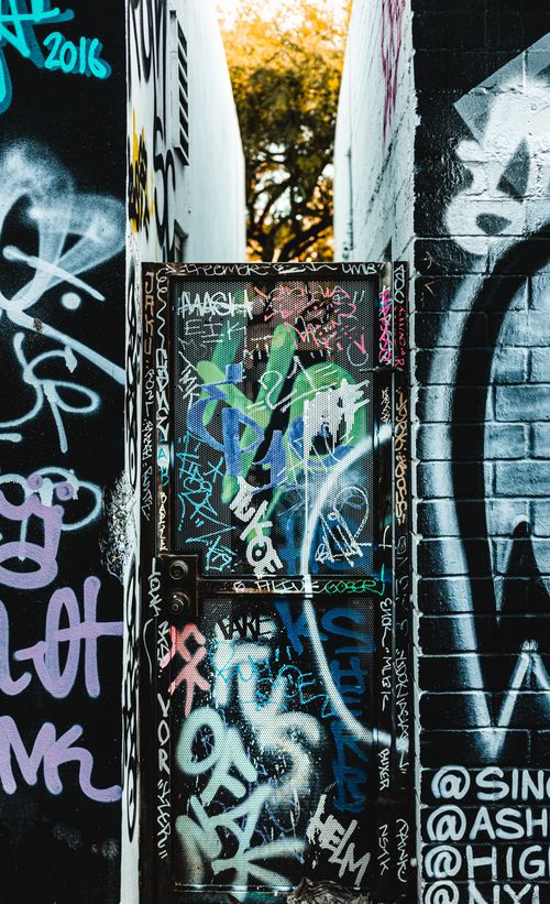 Free Vibrant graffiti artwork covering an alley's brick wall and metal door. Stock Photo