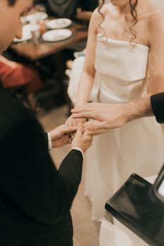 An intimate moment during a wedding ceremony showing the exchange of rings between the couple.