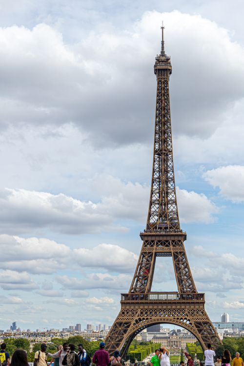 Free Stunning view of the Eiffel Tower against a cloudy sky with visitors below, capturing Paris's iconic landmark. Stock Photo