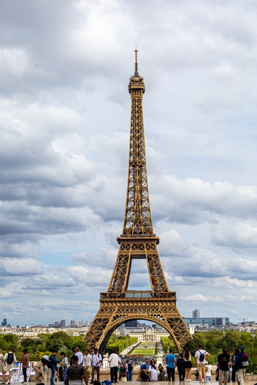 Free Eiffel Tower in Paris with tourists enjoying a cloudy day view. Stock Photo