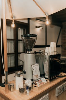Warm interior view of a cafe with an espresso machine, grinder, and coffee cups.