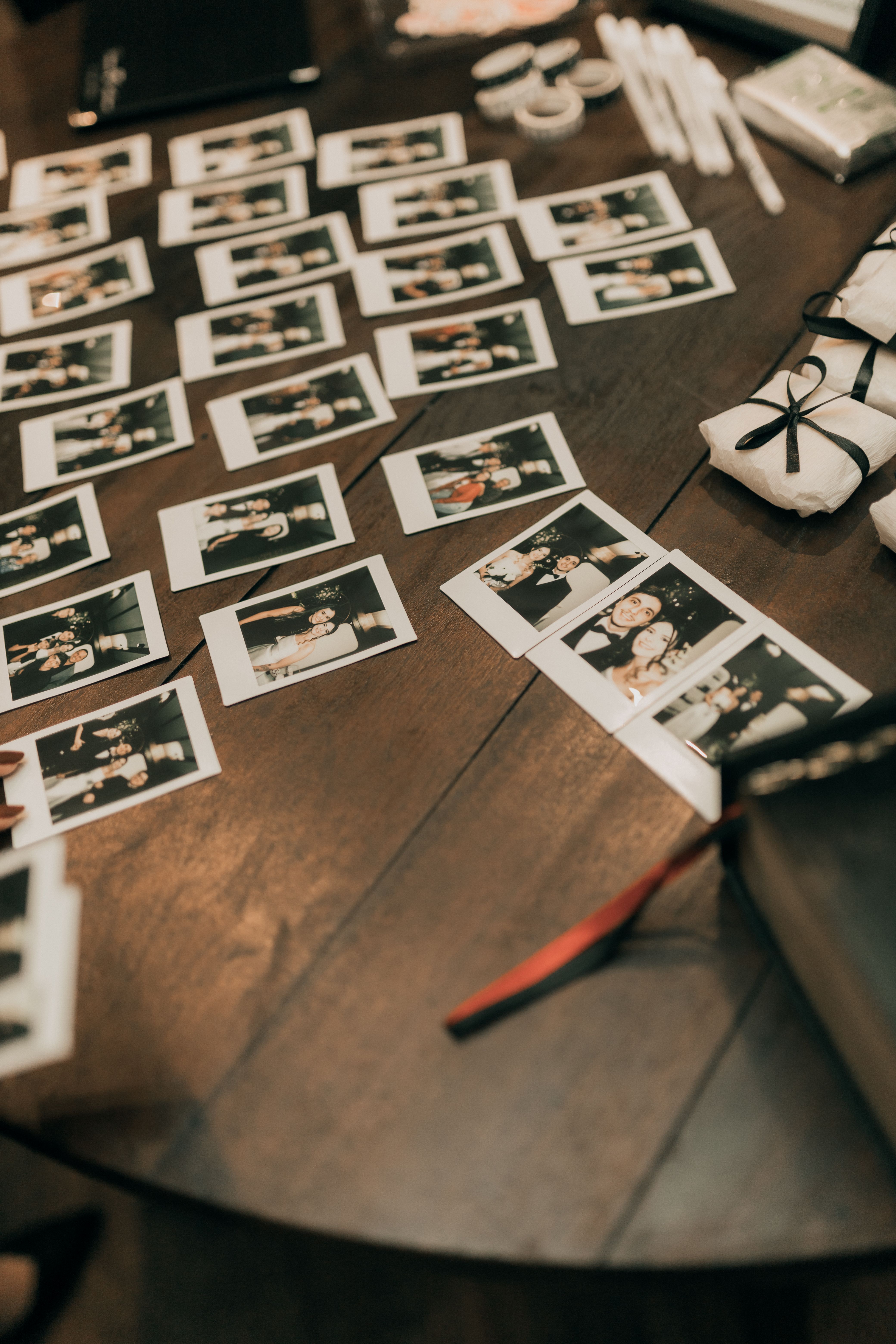 A decorated wooden table filled with instant photos capturing memorable moments. Perfect for scrapbooking themes.