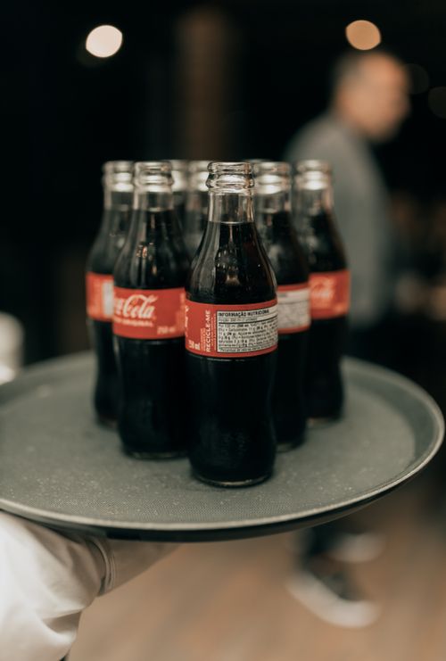 Free Close-up of Coca-Cola bottles on a tray served at an indoor event, offering refreshments. Stock Photo