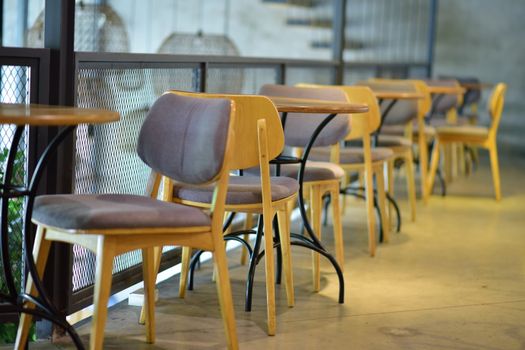 Chic coffee shop interior with modern wooden chairs and tables, perfect for a relaxing ambiance.
