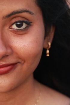 Artistic close-up portrait capturing the beauty of a smiling South Asian woman with dramatic lighting.
