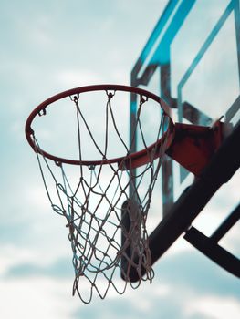 Close-up of a basketball hoop under a clear sky, emphasizing outdoor sports energy.