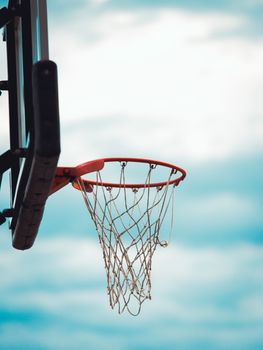 A close-up of a basketball hoop with a net against a bright blue sky, perfect for sports themes.