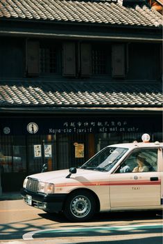 Japanese taxi driving past a traditional building and tourist information center.
