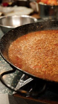 Close-up of authentic Spanish paella simmering in a large pan, showcasing vibrant colors and rich texture.