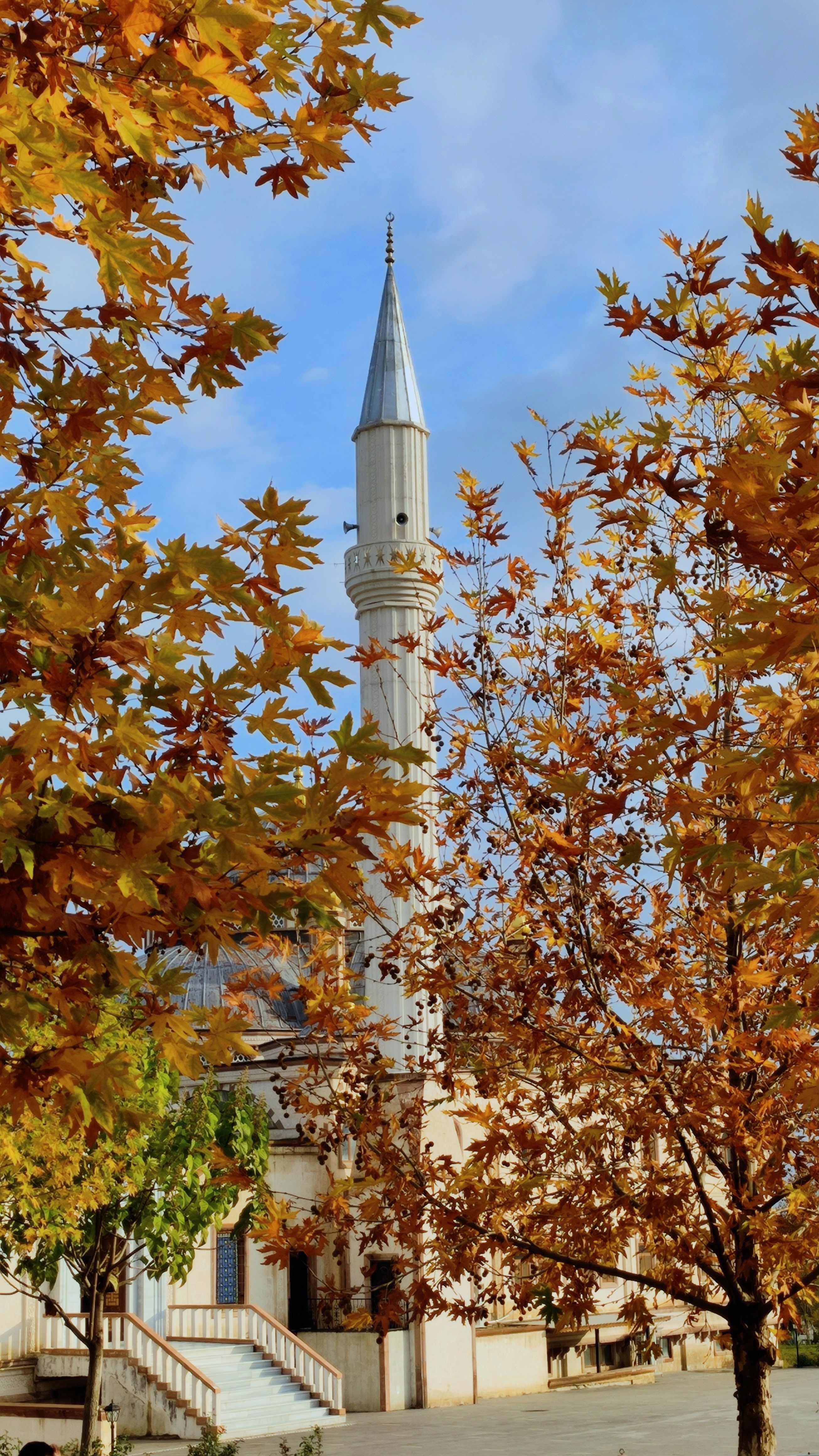 A picturesque mosque framed by vibrant autumn leaves in Adıyaman, Türkiye.