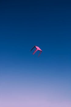 Unique perspective of a pink chair floating in a clear blue sky over Tbilisi, Georgia.