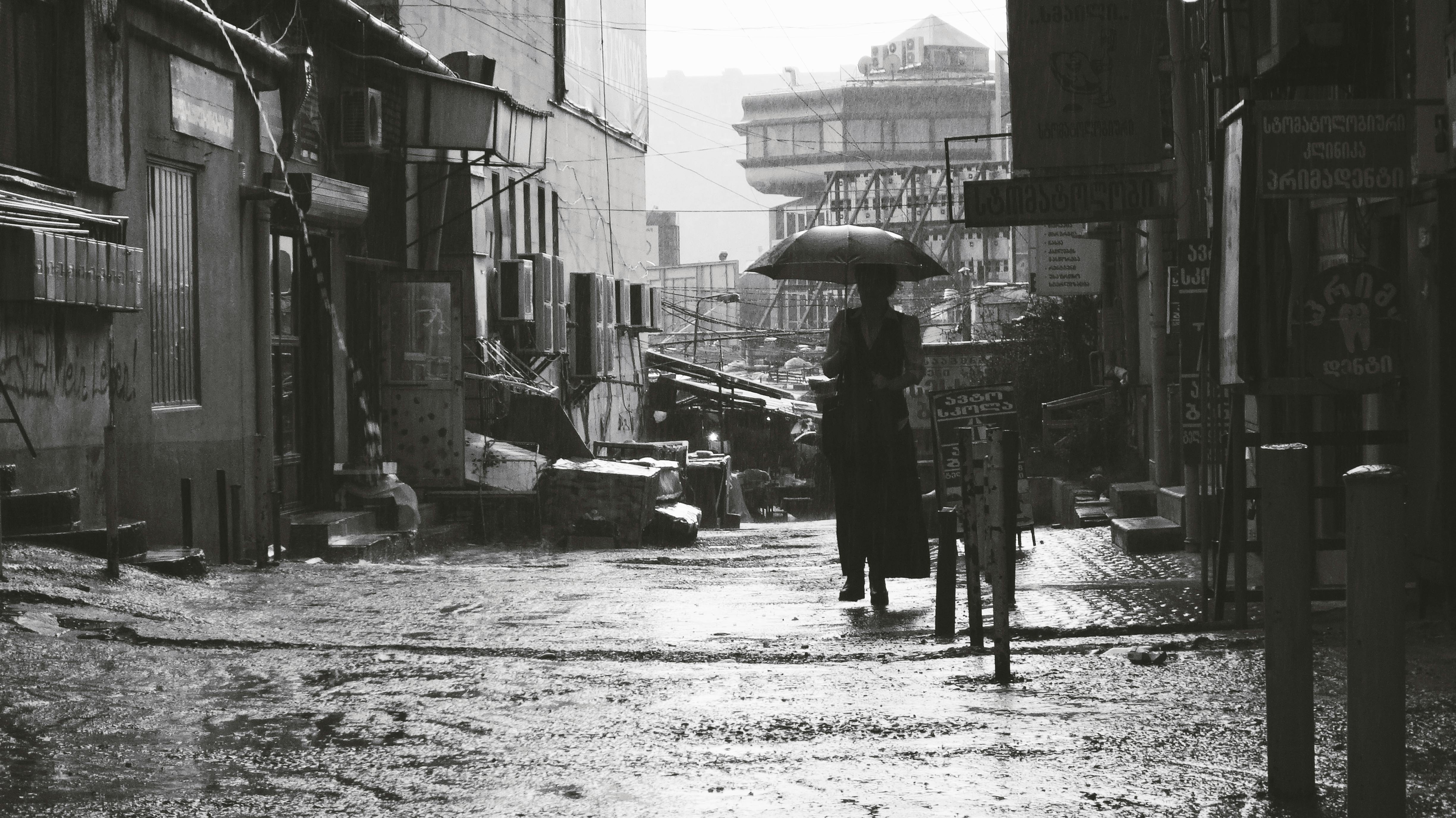 Silhouette of a person walking with an umbrella in a rainy street in Tbilisi, Georgia.