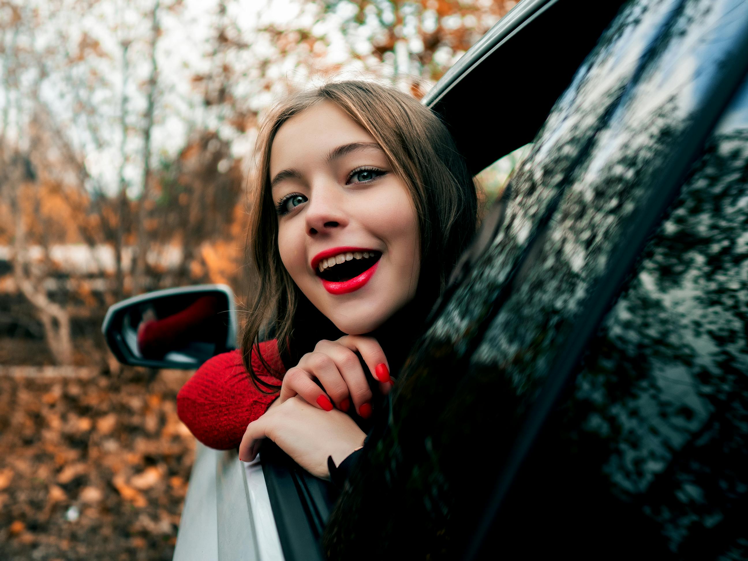 女人快乐地伸出车窗，笑容灿烂地拥抱秋日的风景