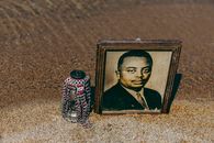 Framed portrait and decorative jar on sandy beach in Bujumbura Mairie, Burundi.